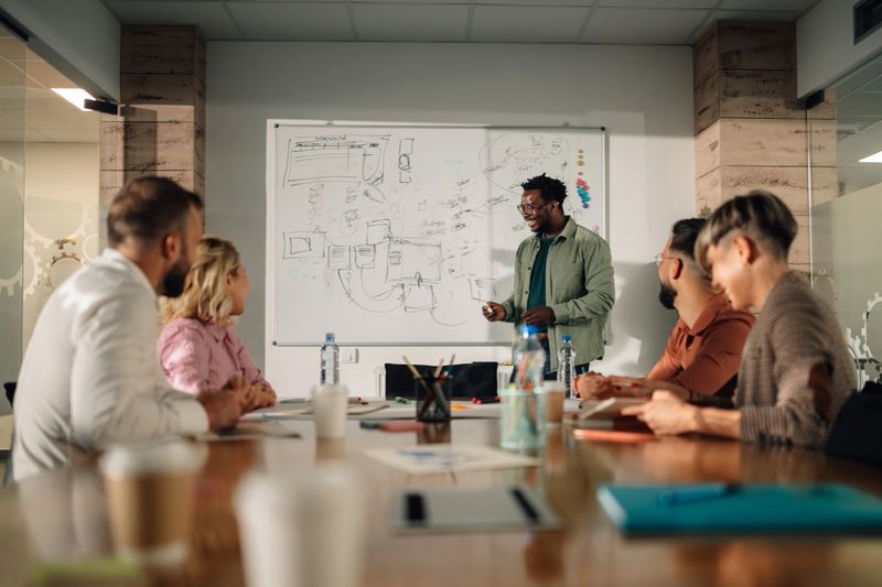 Diverse team of professionals is sitting at a large wooden table in a modern office