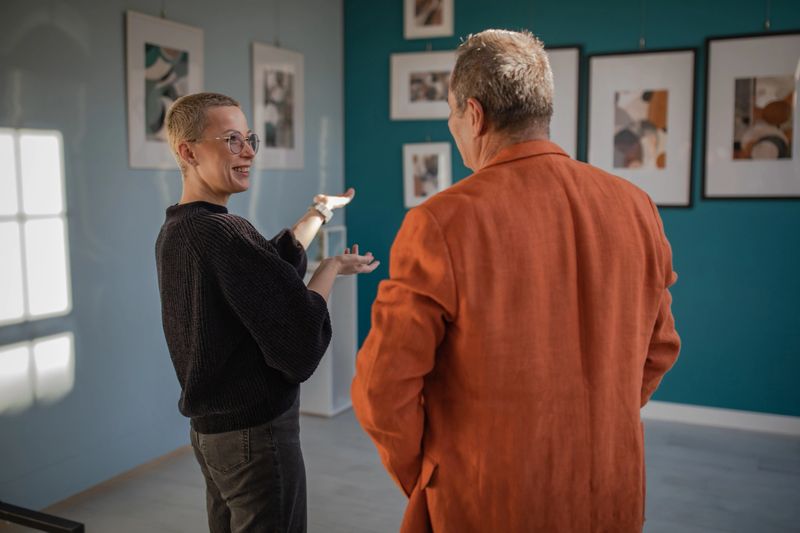 A young artist and a photo gallery owner are talking