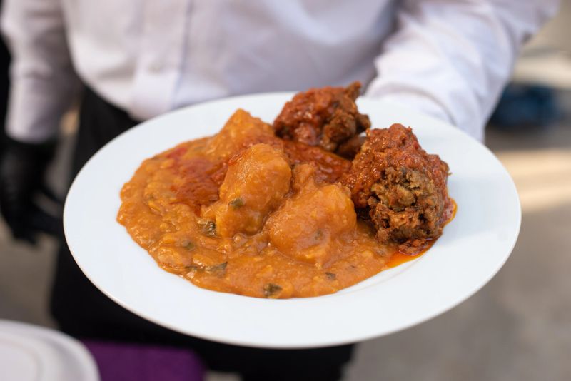 Delighting in tradition, a waiter serves a feast of yam porridge - Asaro and fish  at a special event