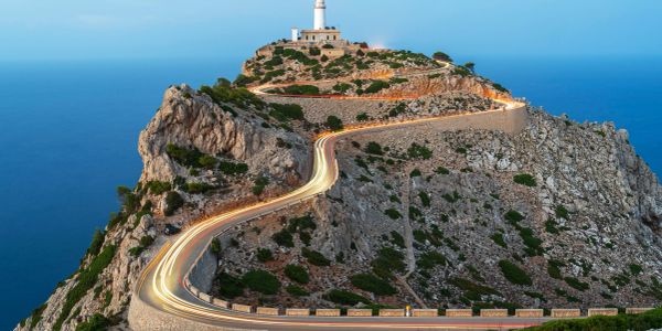 A winding road leading to a lighthouse on a rocky cliff.
