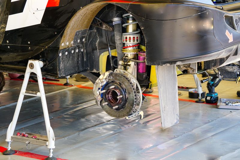 Rally car maintenance in service park, rear wheel high performance suspension and brake disc with caliper
