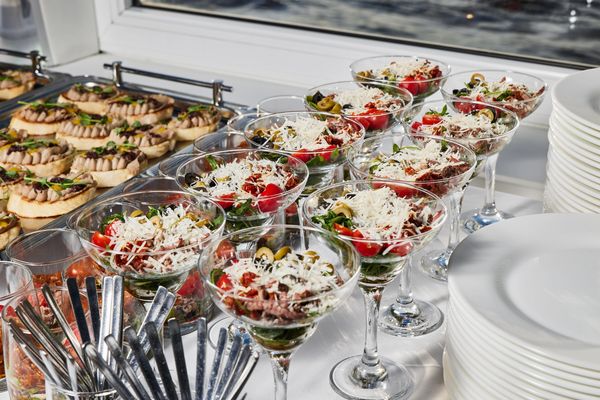 Elegant appetizers served in martini glasses and mini tartlets on a buffet table.