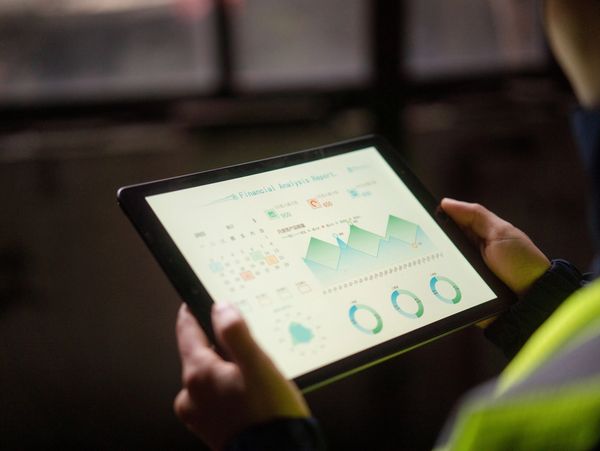 Person holding a tablet displaying a financial analysis report with charts and graphs.