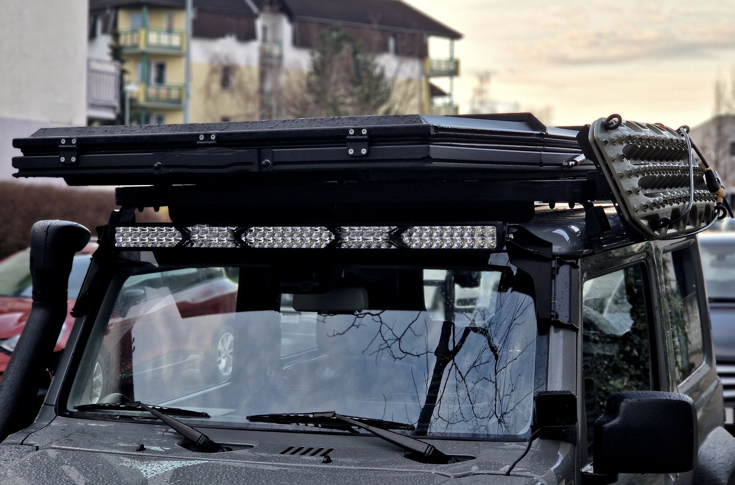 Off-road vehicle with roof rack and LED light bar.