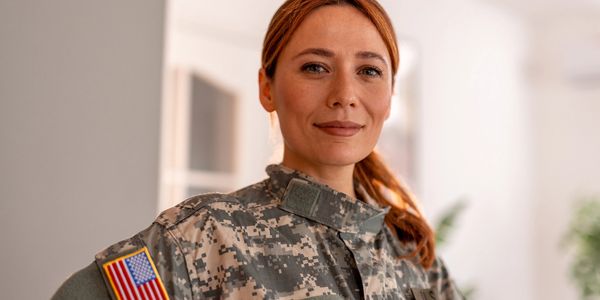 Confident female soldier in military uniform with American flag patch.
