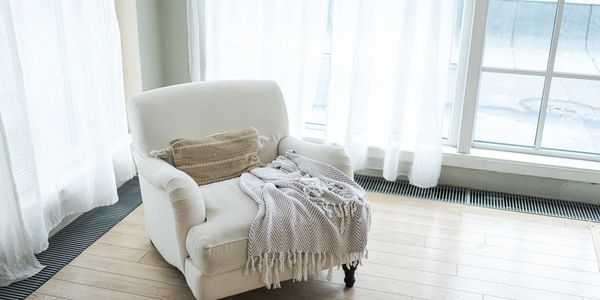Calm armchair, with blanket, soft natural light, symbolizing rest, reflection, and being truly heard