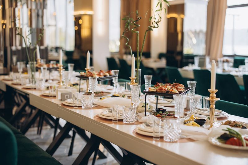 Luxurious banquet table is set for wedding reception with delicious appetizers, candles and crystal glasses, creating a festive and elegant atmosphere