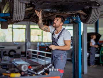Mechanic inspecting a car lifted in a garage.