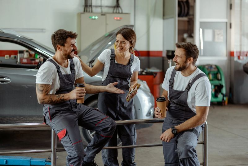 In a Bustling Automotive Service Center, a Man and Woman Dressed in Work Attire Share a Smile During a Well-deserved Break. The Photo Highlights a Moment of Relaxation Amidst the Busy Workshop, Reflecting Teamwork and a Positive Atmosphere in a Productive Workplace.