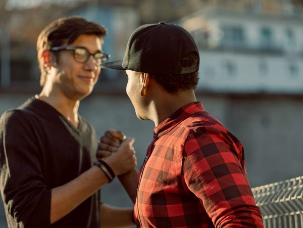 Two friends greeting each other with a handshake outdoors.