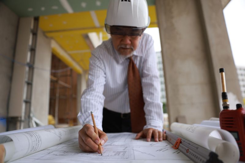A senior project engineer man using building plans or drawings in the workplace of the construction site.