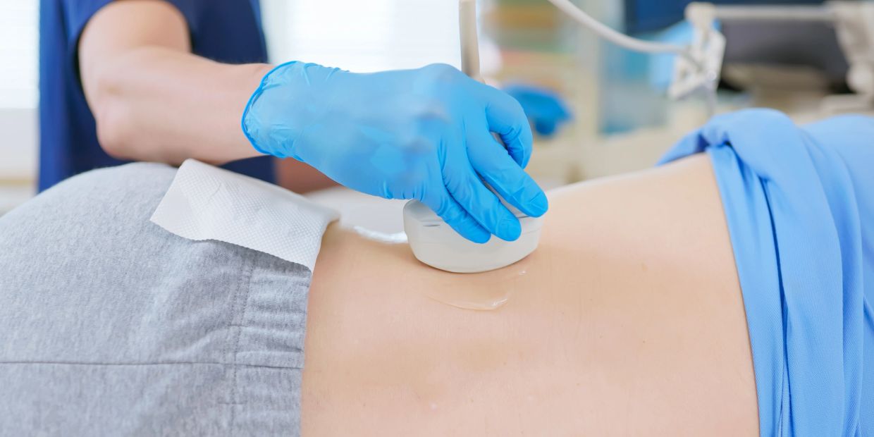 Medical professional performing an ultrasound scan on a patient's abdomen.