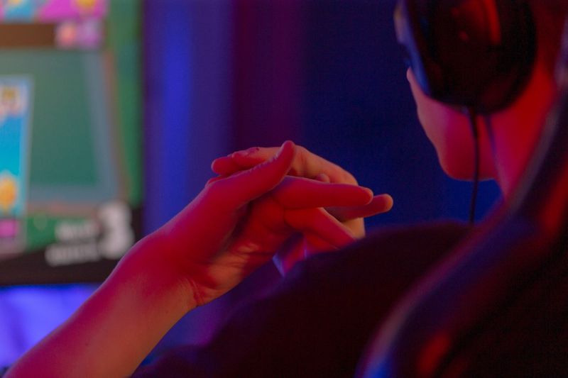 A focused gamer with headphones skillfully plays in a vibrant, colorful, energetic gaming environment