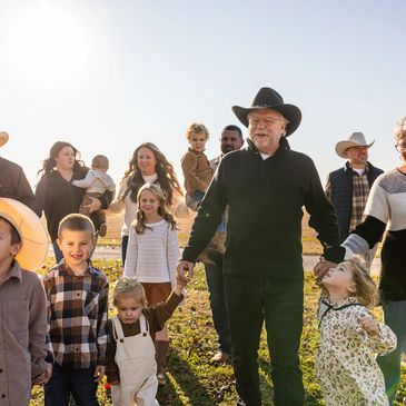 Large family walking outdoors on a sunny day, holding hands and smiling.