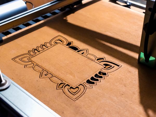 Laser cutting a decorative pattern on a leather sheet.
