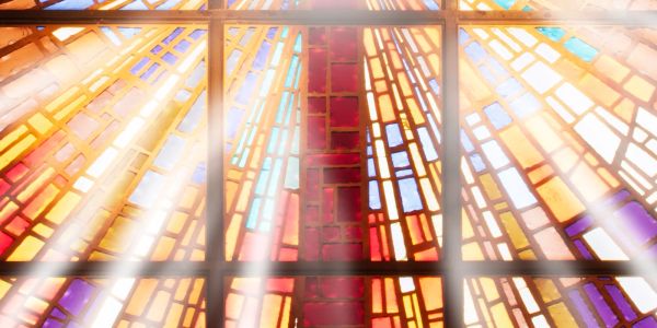 Sunlight streams through vibrant stained glass windows with a cross at the center.