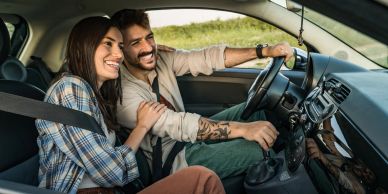 Couple enjoying a car ride together, smiling.