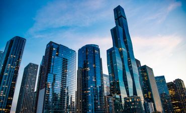 Modern glass skyscrapers against a blue evening sky.