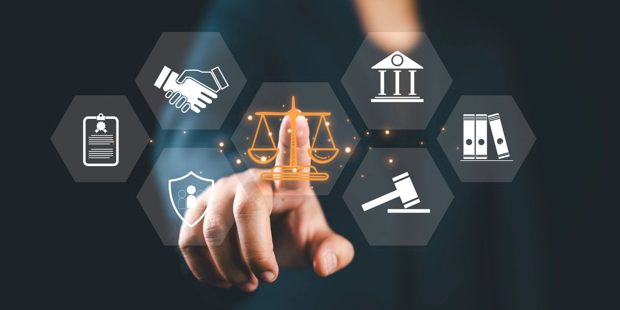 Person pointing at screen with law scales icon, symbolising legal compliance and regulations.