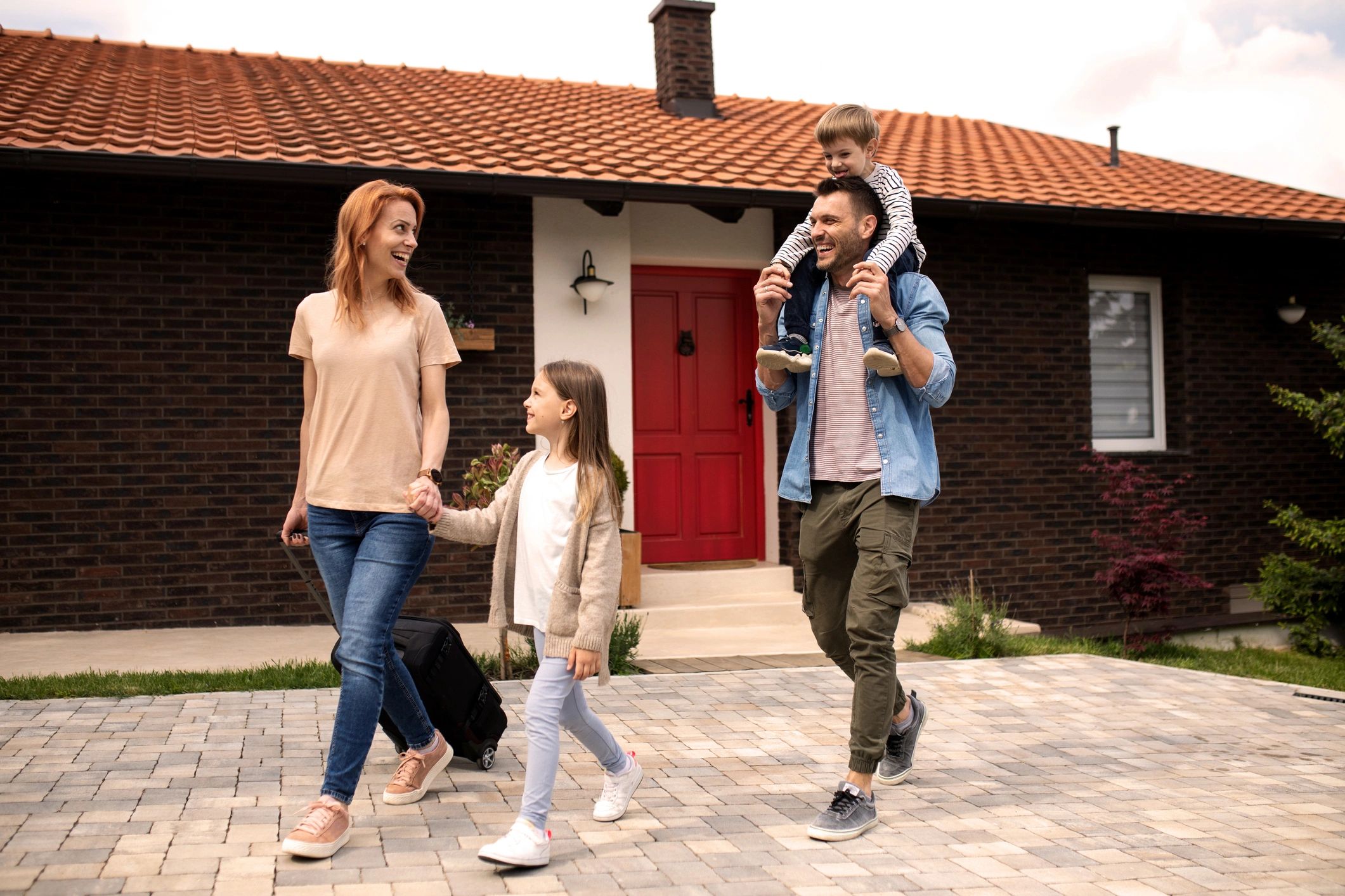 Happy family leaving home with luggage, smiling and enjoying their time together.
