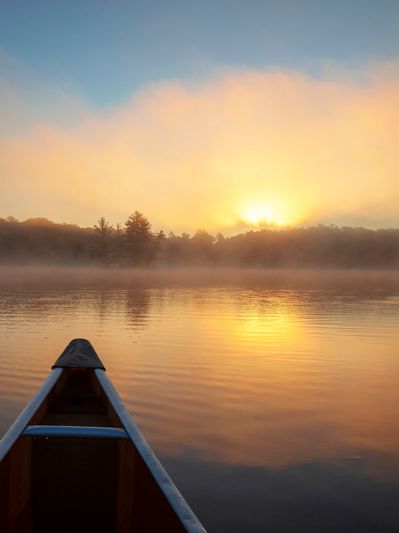 Canoeing at sunrise over a calm, misty lake.