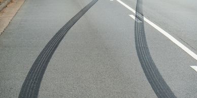 Dark skid marks on a road curving to the right.