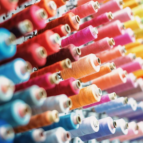 Rows of colorful thread spools arranged on a rack.