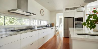 Bright modern kitchen with white cabinets and wooden floor.