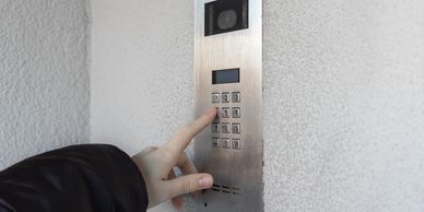 Person entering a code on a stainless steel access control keypad system for secure building entry 