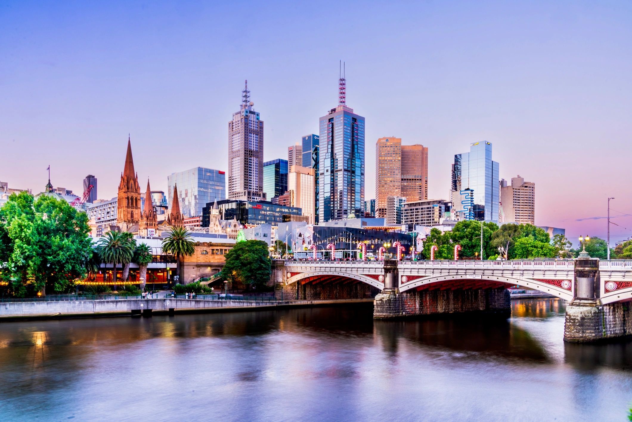 City skyline with bridge and river at sunset.