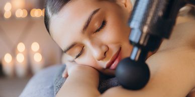 Woman enjoying a relaxing massage with a massage gun.