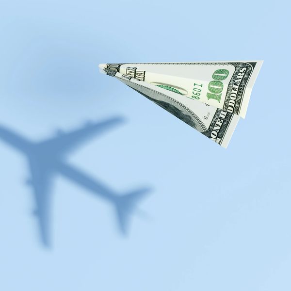 Paper airplane made from a hundred-dollar bill flying in the sky.