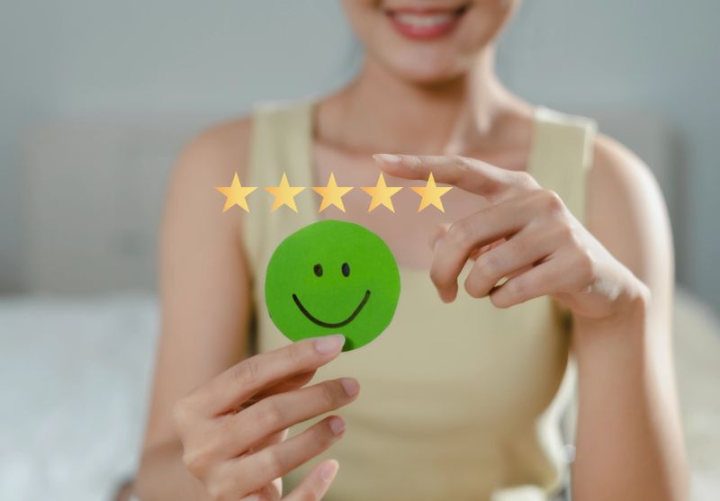 Customer's hand chooses to give 5 stars to show feedback with smiley face symbol, service evaluation, satisfaction concept.
