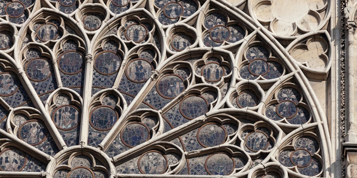 Detailed close-up of a Gothic stained glass rose window with intricate tracery.