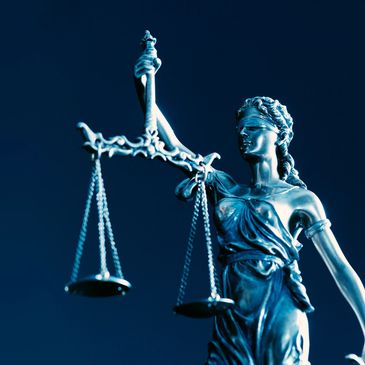 Statue of Lady Justice with scales against dark blue background.