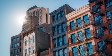 Sunlight shines on colorful urban buildings with fire escapes.