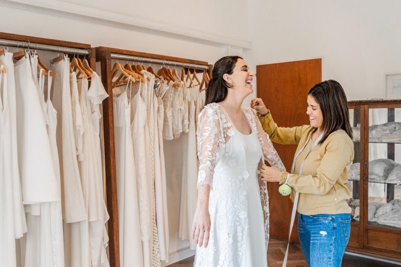 Seamstress adjusting the bride's dress in a bridal shop