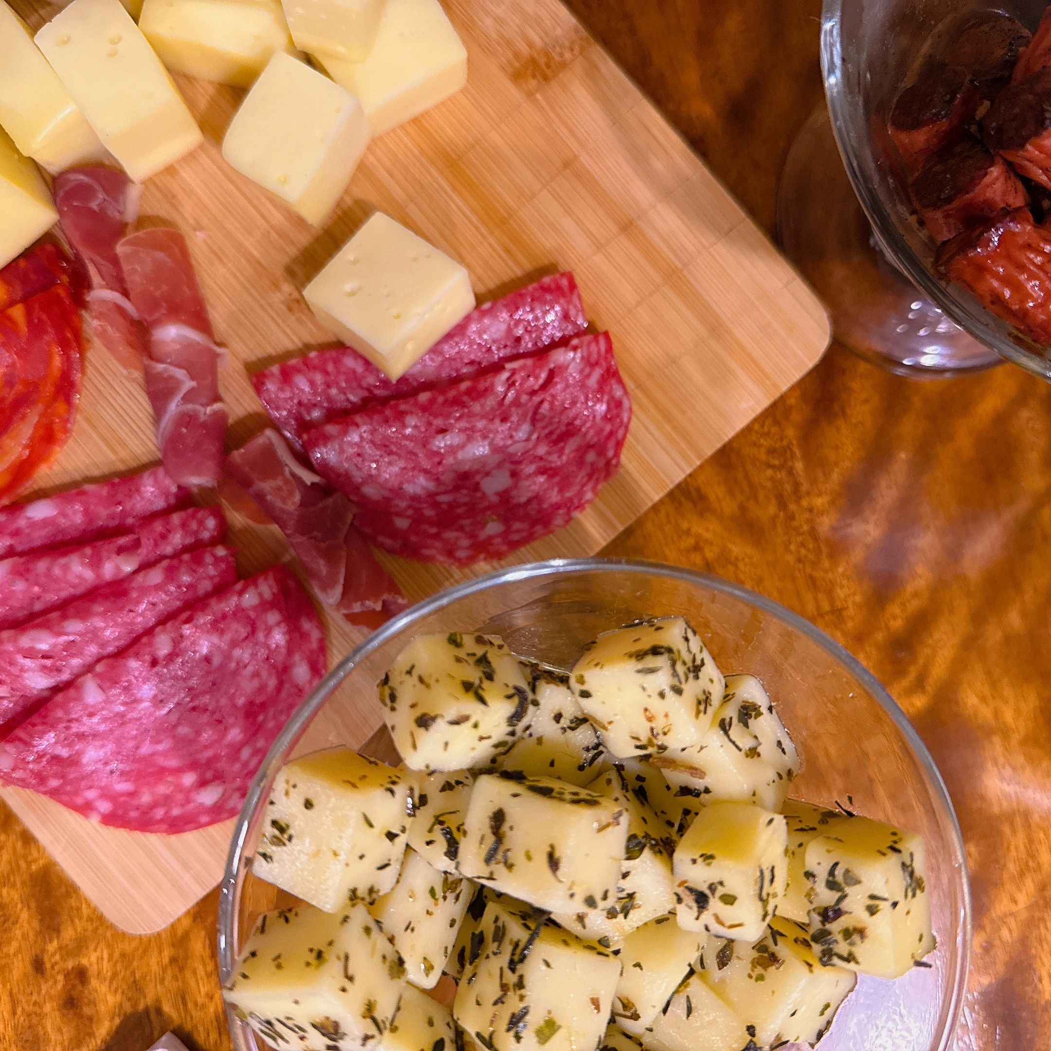 Cheese and charcuterie board with herb-seasoned cheese cubes.