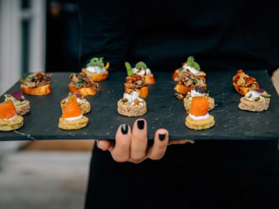 Assorted gourmet appetizers on a black slate tray.