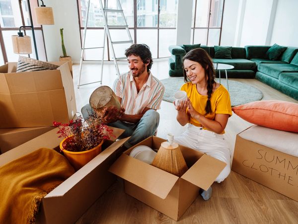 Couple unpacking boxes in a bright living room during a move.