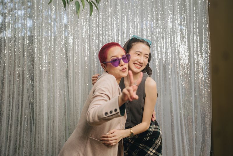 Group of lgbtq friends having fun posing with a photo booth at a wedding at a restaurant.