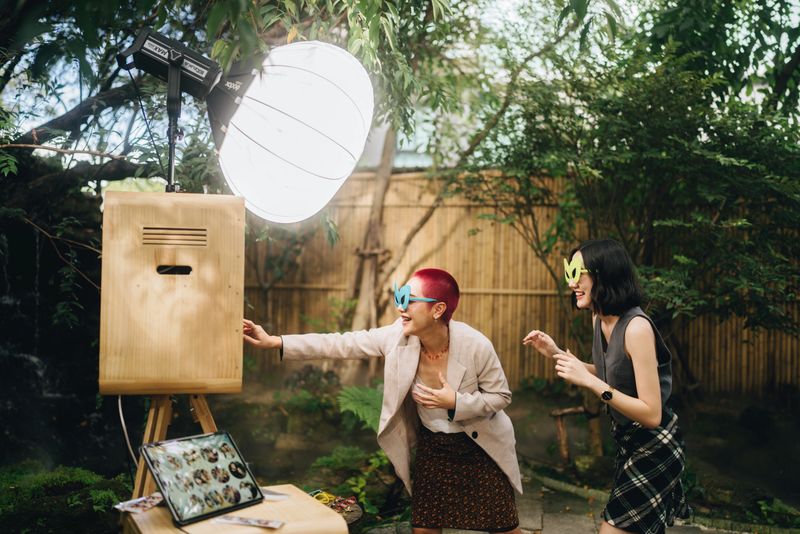 Female friends having fun at a wedding in front of a photo booth Take a photo and choose to save it on a mobile phone.
