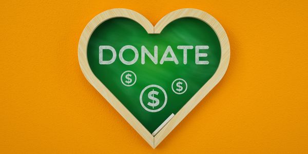 Heart-shaped chalkboard with 'DONATE' and dollar signs on an orange background.