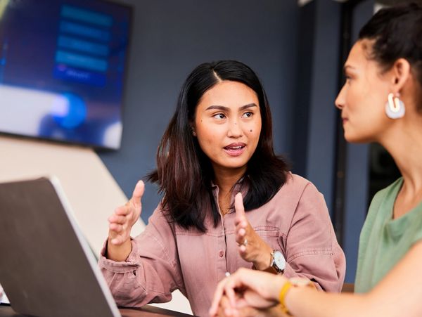 Two women engaged in a focused discussion in an office setting.