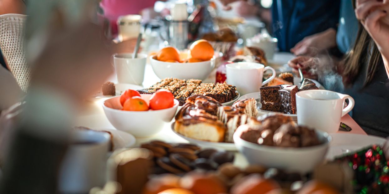 People gathered around a table with tea and desserts.