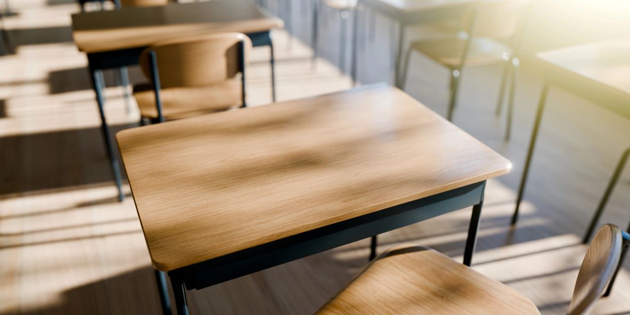 Empty wooden school desks in sunlight.