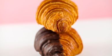 Two croissants stacked, one plain and one half chocolate-coated.