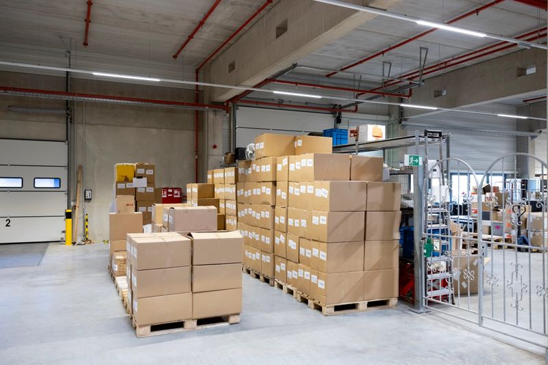 Stack of cardboard boxes over wooden pallets at the loading dock inside a distribution warehouse. The organized setup highlights efficient logistics and preparation for shipment.