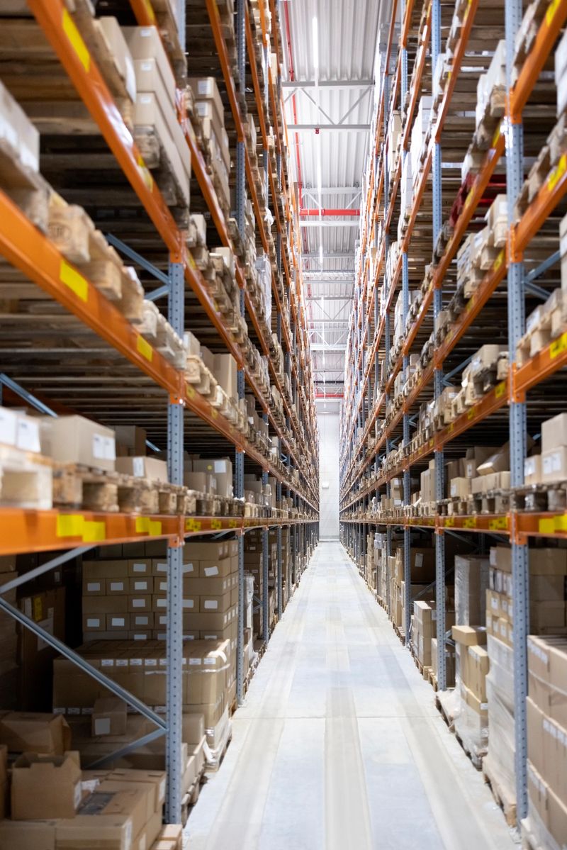 Distribution warehouse interior with shelves and racks holding cardboard boxes. The modern warehouse showcases an organized and efficient environment for managing and distributing goods.