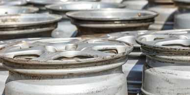 Stacks of used and dirty car wheel rims in an outdoor setting.